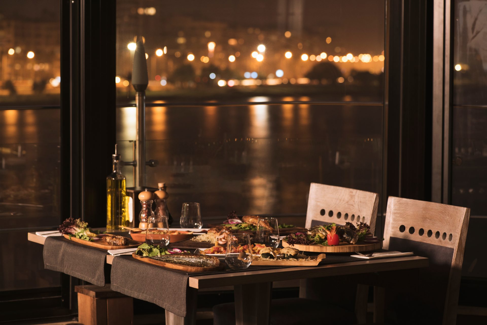 Mesa puesta junto al ventanal de un restaurante de noche, atmósfera de fine dining